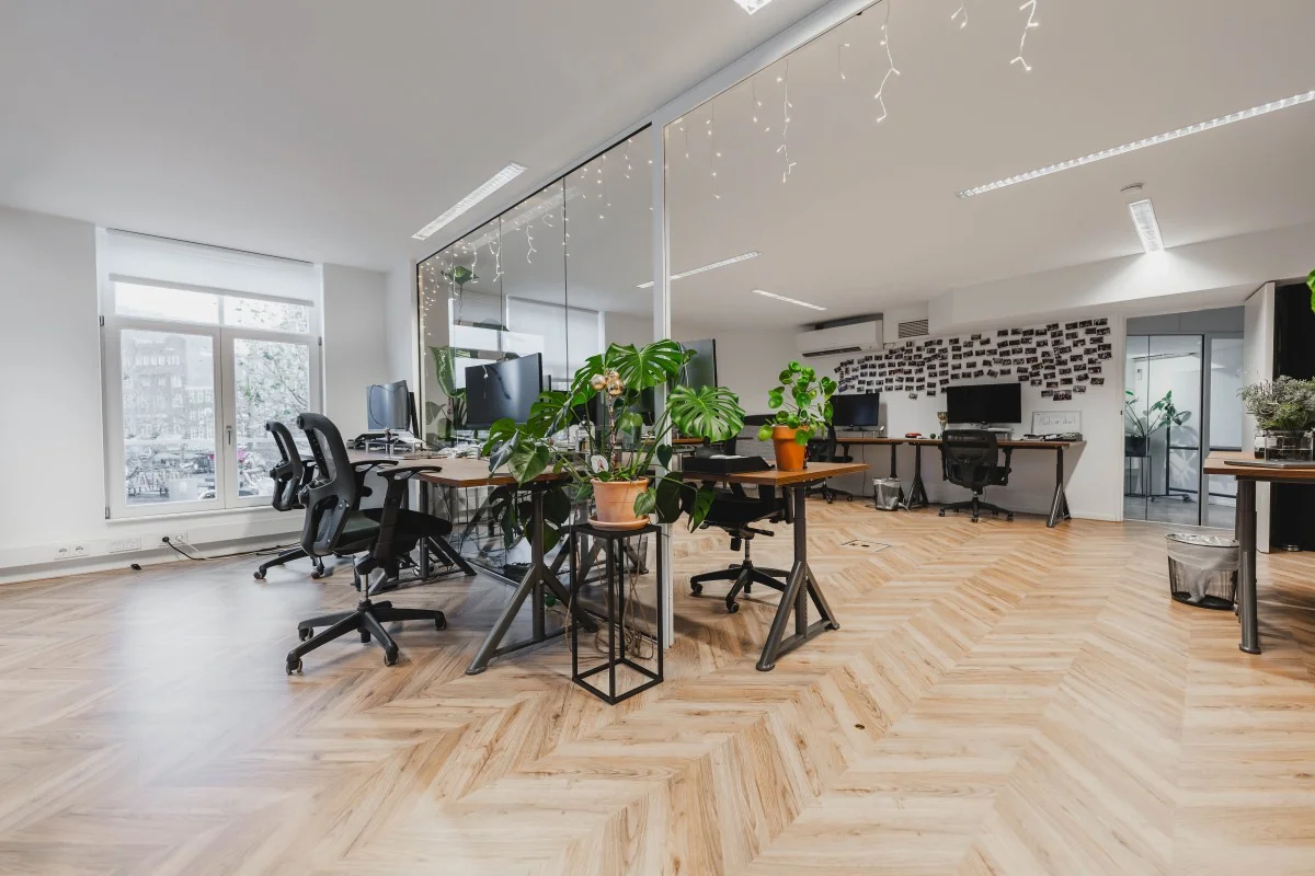 Modern kantoorinterieur aan de Korte Reguliersdwarsstraat met flexibele werkplekken, planten en glazen scheidingswand.